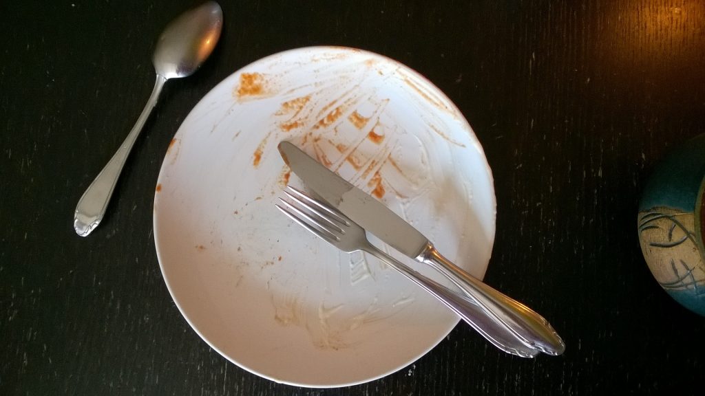 Ein leerer Teller mit Essensreste und Besteck 